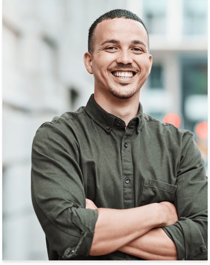 A man stands casually crossing his arms and smiling.