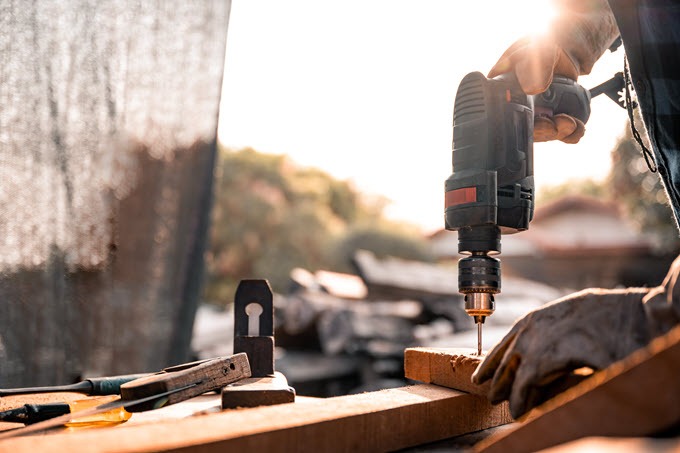 Two hands using a power drill on a home improvement project.
