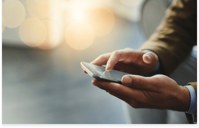 A close up image of a man's hands holding a cell phone.